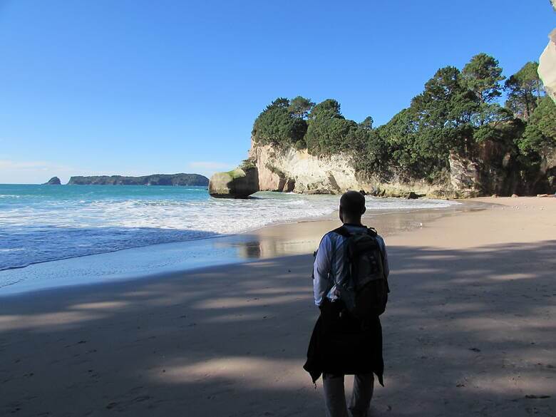 Mann steht in der Bucht Cathedral Cove in Neuseeland 