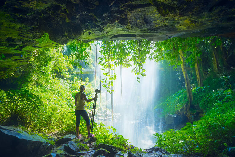 Frau hinter einem Wasserfall im Dorrigo-Nationalpark in Australien