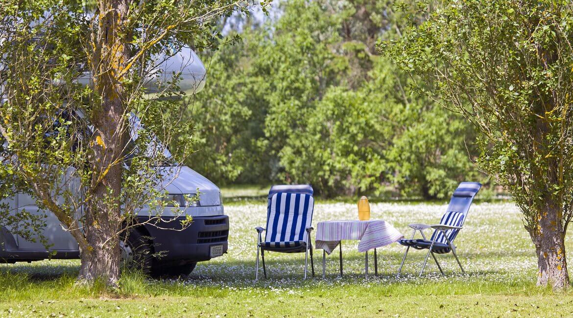 Wohnmobil mit Campingtisch und -stühlen im Freien