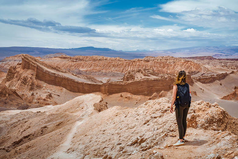 Frau mit Rucksack blickt auf die Felsen in der Atacama-Wüste in Chile