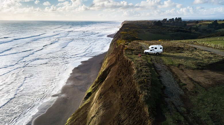 Zwei Menschen sitzen vor ihrem Camper in Chile direkt am Meer