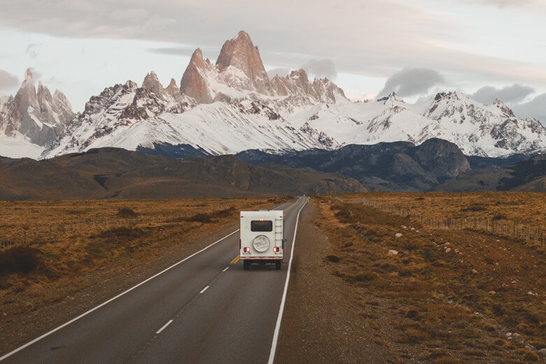 Wohnmobil fährt durch Chile auf schneebedeckte Berge zu