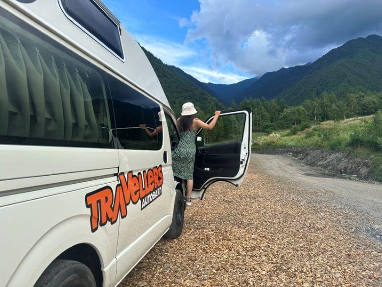 Frau schaut in Japan aus dem Camper auf die Berge und die Natur 