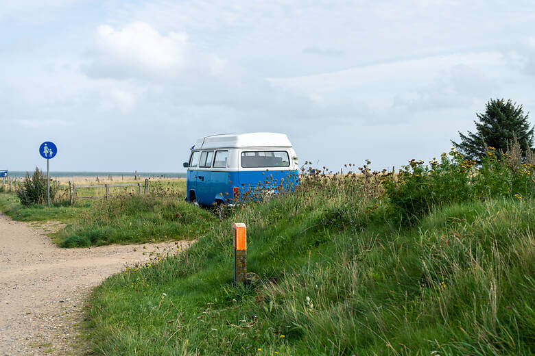 Blauer Camper parkt an der Nordsee am Strand 