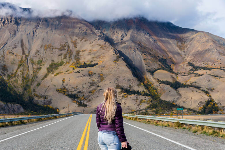 Frau auf dem Alaskan Highway im Herbst