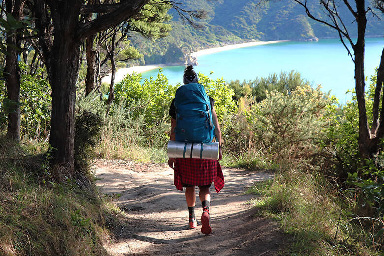 Frau wandert durch den Abel Tasman National Park in Neuseeland mit Blick auf das Meer