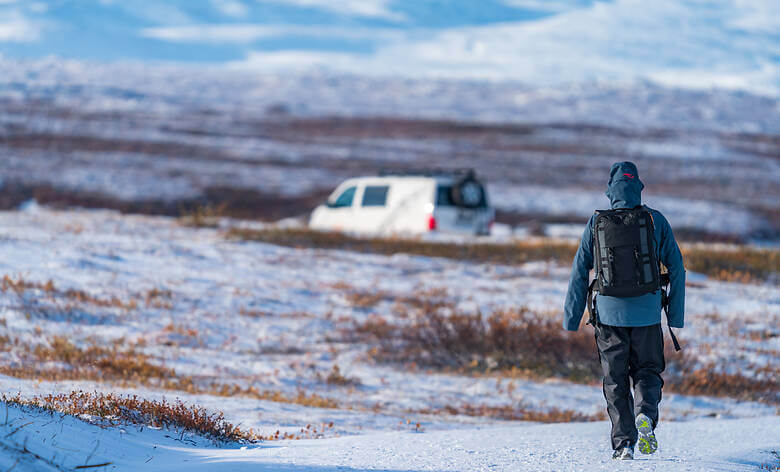 Person wandert im Schnee zurück zum Campervan