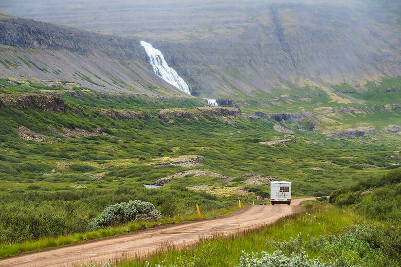 Wohnmobil fährt über eine Schotterstraße in Island auf den Westfjorden